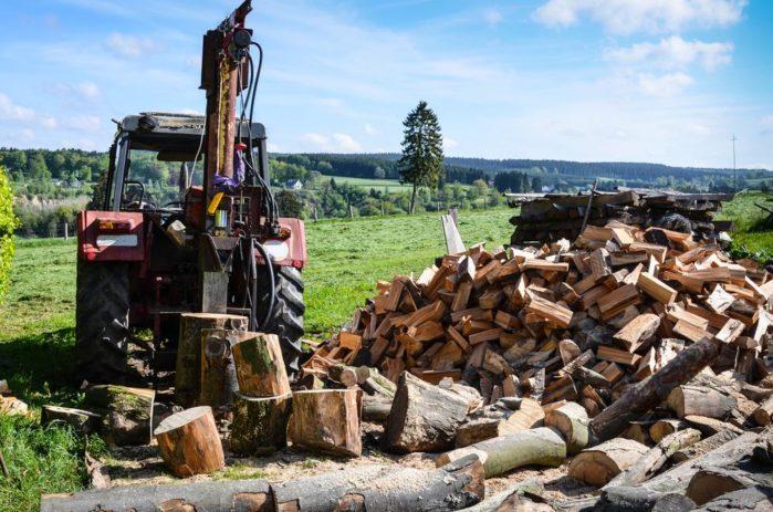 Old tractor with hydraulic powered log splitter and pile of firewood