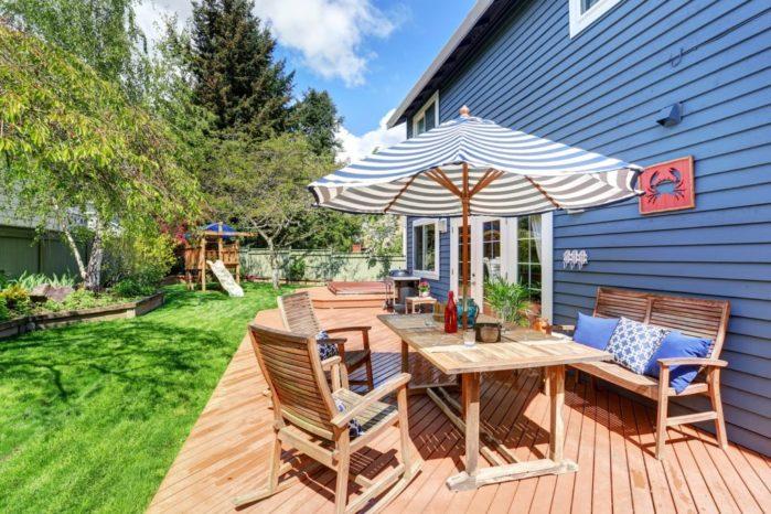 Wooden Walkout Deck In The Backyard Garden Of Blue Siding House