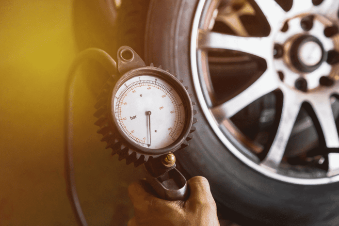 Close up mechanic inflating tire and checking air pressure with gauge