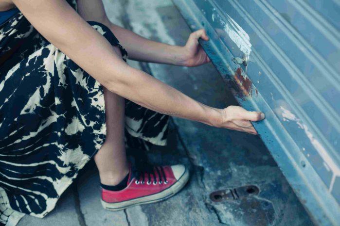 A woman is unlocking and opening a garage door