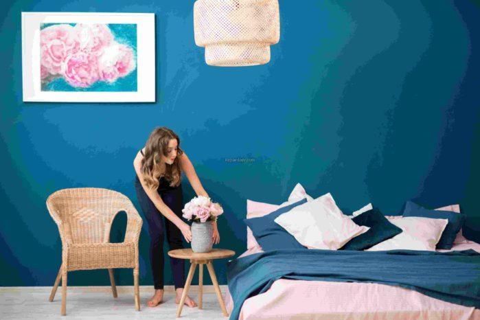 Young woman decorating bedroom with beautiful flowers at home