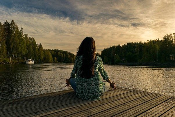 girl meditating in front of lake