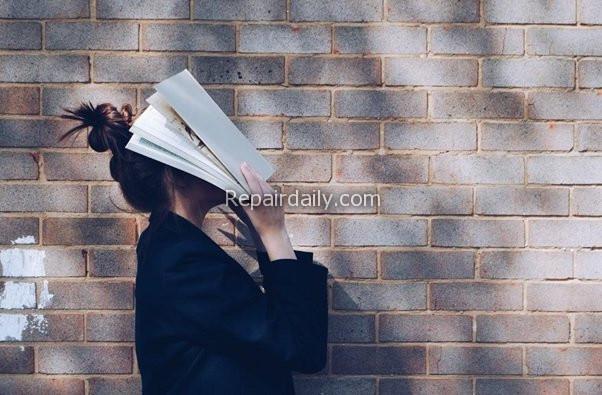 student hiding her face with book